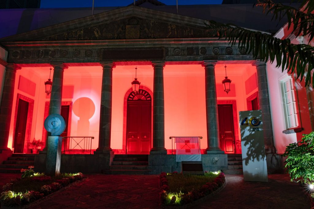 La fachada del Parlamento de Canarias luce la bandera de Cruz Roja y se iluminó de ese color por el Día Mundial de la Cruz Roja
